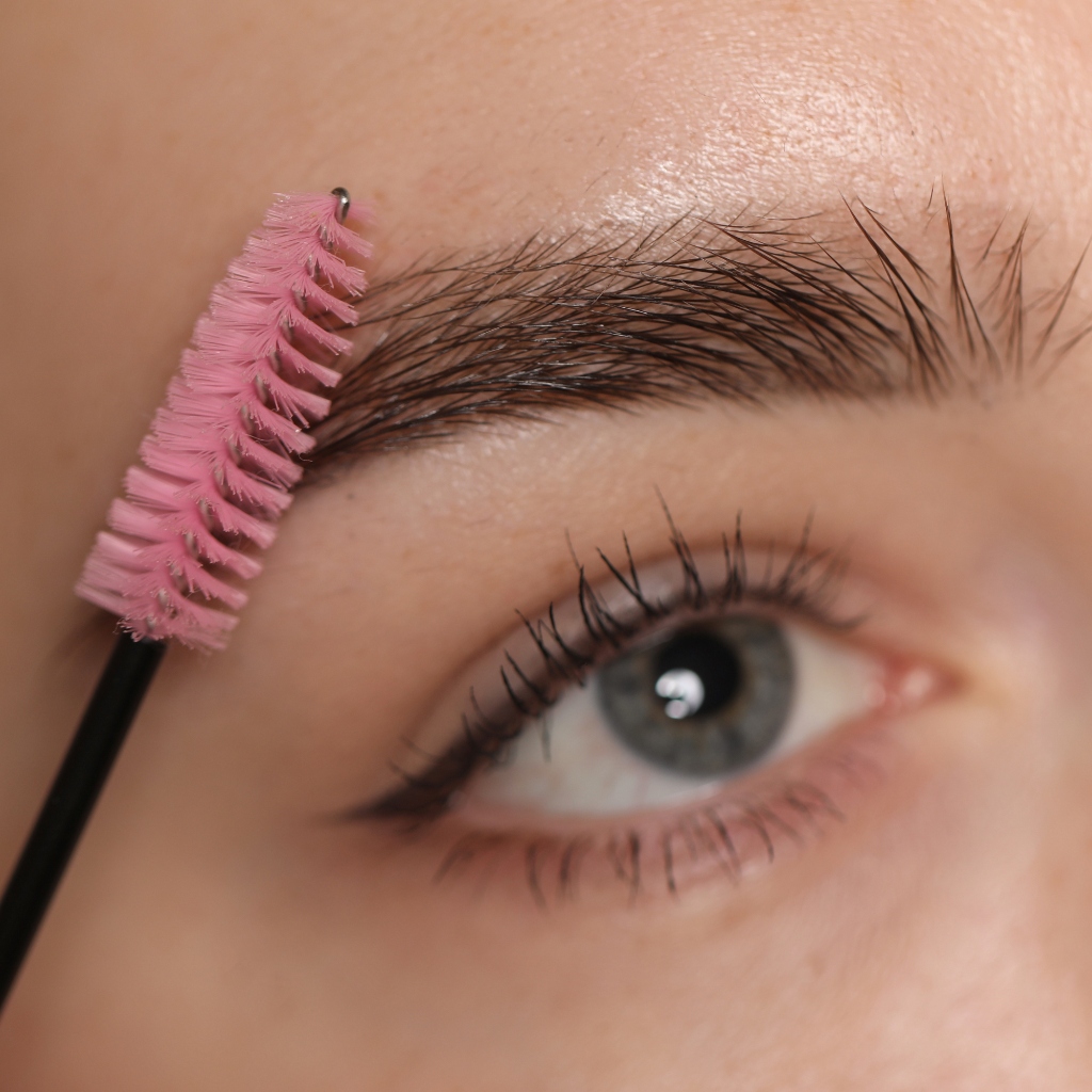 Design de sobrancelhas com escova profissional rosa.